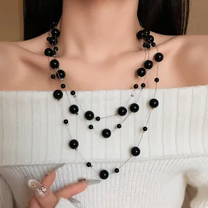 Elegant multi-layered black pearl necklace detail shown on an off-shoulder sweater