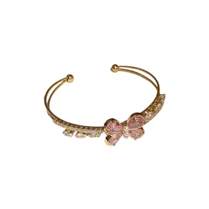 Elegante brazalete abierto de doble capa dorado con una mariposa de circón rosa.
