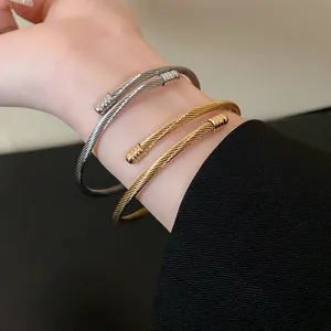Detailed macro view of minimalist gold and silver twisted cable wire bracelets on wrist