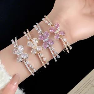 Detalle de brazaletes abiertos de doble capa con mariposas de circón en la muñeca.