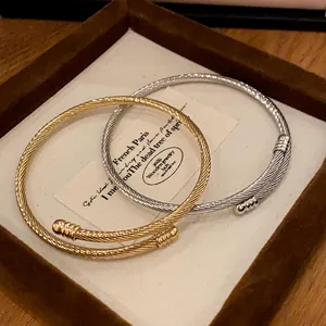 Detail view of twisted cable metal bangles in gold and silver on a display tray