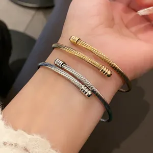 Close-up of twisted metal cable bangles in gold and silver finish on model wrist