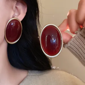 Macro detail shot of vintage oval stud earrings with deep red stone in gold frame
