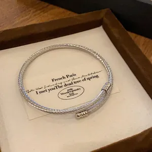 Detailed view of a silver-toned metal twisted cable bangle bracelet in a gift box