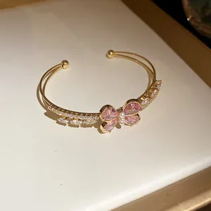 Vista detallada del elegante brazalete dorado con mariposa de circón rosa y perlas