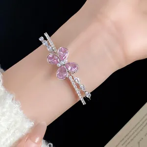 Vista detallada de un brazalete de mariposa de plata con circón rosa en una muñeca.