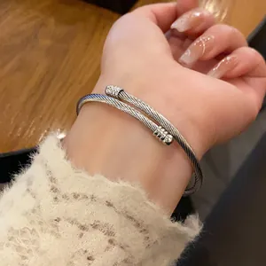 Close-up view of a minimalist silver twisted cable woven cuff bracelet worn on a wrist