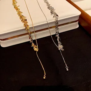 Gold and silver wheat leaf tassel necklaces with a minimalist style displayed on a jewelry box