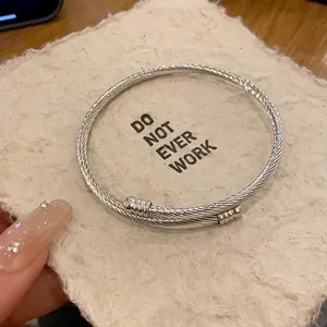 Close-up detail of a silver twisted cable bangle on a textured background