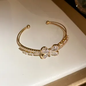 Detalle del brazalete abierto dorado de doble capa con motivo de mariposa en circonitas