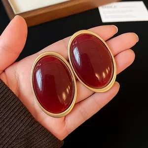 Detailed view of vintage large oval stud earrings in deep red resin and gold frame