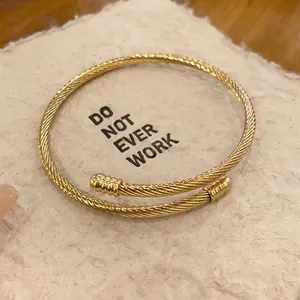 Detailed macro view of a gold twisted cable open cuff bracelet on a textured card