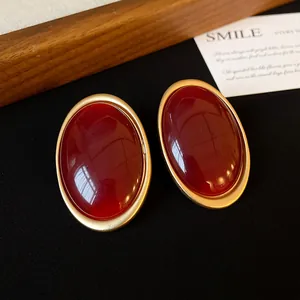 Close-up of vintage oval stud earrings with deep red cabochons and gold frames