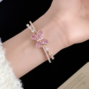 Elegante brazalete abierto de doble capa con mariposa de circonita rosa puesto en la muñeca.