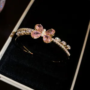 Primer plano de brazalete de mariposa con circonita rosa brillante sobre terciopelo negro.