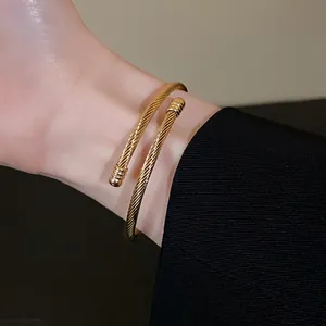 Detailed view of an elegant gold twisted wire open cuff bracelet worn on a person's wrist