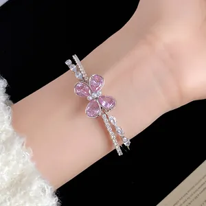 Detalle de un brazalete abierto de doble capa con una mariposa de circón rosa.