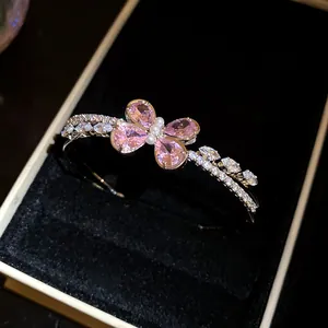 Primer plano de elegante pulsera abierta de doble capa con mariposa de circón rosa y perlas.