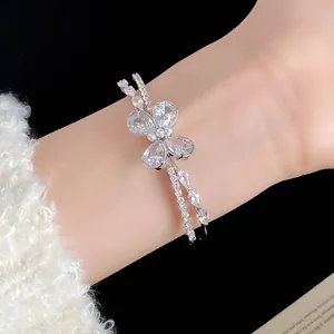 Elegante brazalete abierto de doble capa con mariposa de circón en una muñeca fina