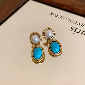 Detailed view of vintage French gold earrings with faux pearl and turquoise stone