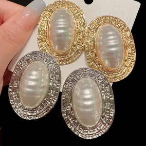 Dettaglio macro di orecchini vintage ovali con perle a righe e bordi strutturati