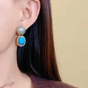 Detail shot of vintage French-style faux pearl and turquoise drop earrings on model