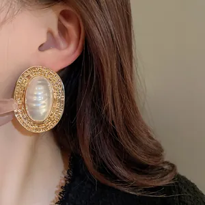 Dettaglio ravvicinato di orecchini a perno vintage francesi ovali con perle a strisce.