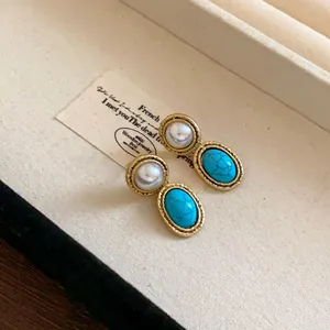 Close-up of French vintage gold earrings with faux pearl and turquoise stone