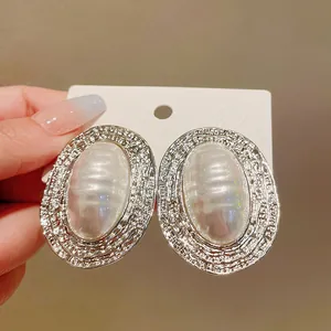 Dettaglio di orecchini ovali in argento retrò con perla a righe e bordo martellato