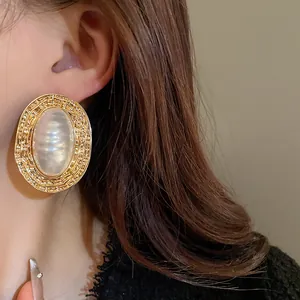 Dettaglio macro di un orecchino ovale in stile palazzo vintage con perla su una modella