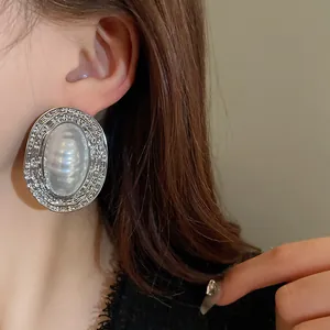 Dettaglio di un orecchino ovale in stile corte francese con perla a righe sull'orecchio.