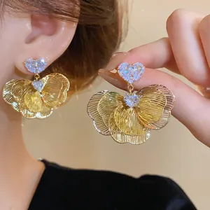 Close-up of gold-plated flower earrings featuring sparkling heart-shaped zircons