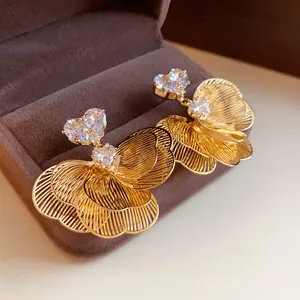 Close-up of gold-plated floral earrings with heart-shaped zircons in a brown gift box