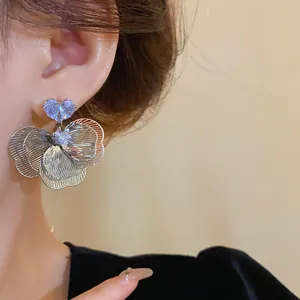 Detailed macro shot of silver plated heart-shaped zircon flower earrings on ear.