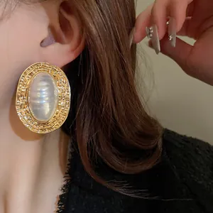 Primo piano di un orecchino ovale dorato vintage con perla a righe sull'orecchio
