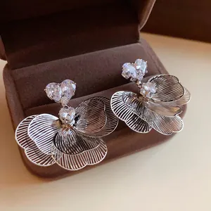Detail of flower-shaped stud earrings with zircon crystals on a brown velvet box