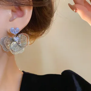 Elegant flower zircon stud earrings with heart crystal detail on model ear
