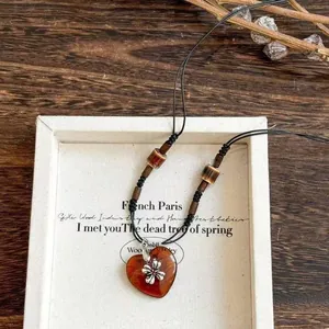 Close-up of the ethnic heart-shaped pendant and flower charm on a beaded cord necklace