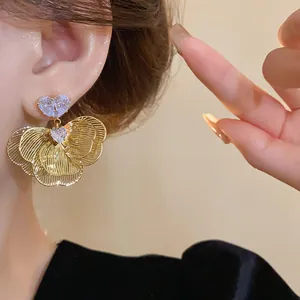 Detailed macro shot of elegant gold-plated flower earrings with heart-shaped zircons.