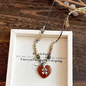 Detail view of a vintage beaded heart pendant necklace with ethnic flower accents.