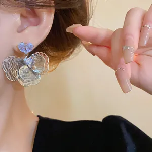 Close-up view of elegant silver flower earrings with sparkling zircons worn by a model