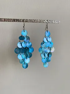 Détail de boucles d'oreilles pendantes en nacre bleue avec crochets argentés élégants