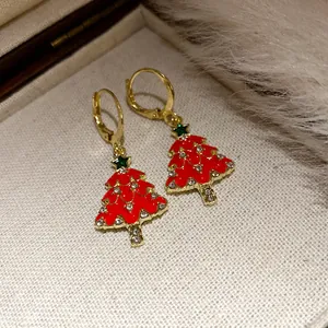Close-up detail of gold Christmas tree drop earrings with red enamel and rhinestones