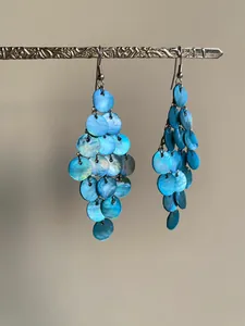 Gros plan détaillé de boucles d'oreilles à pampilles en nacre bleue sur support argenté