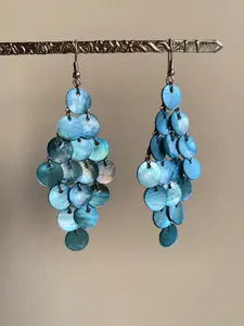 Gros plan sur des boucles d'oreilles à pampilles en nacre bleue naturelle et forme circulaire