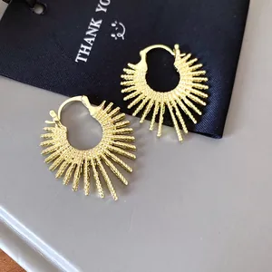 Nahaufnahme goldener Creolen im Sonnenstrahl-Design mit strukturierter Feuerwerk-Optik