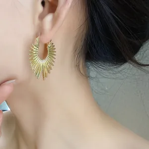 Nahaufnahme von goldenen Feuerwerk-Creolen am Model mit elegantem und einzigartigem Design.