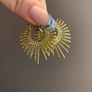 Detailansicht goldener unregelmäßiger Feuerwerk-Ohrringe mit strukturiertem Sonnenstrahl-Design