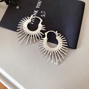 Detailansicht silberner Sunburst-Creolen im Feuerwerk-Design auf schwarzem Geschenkanhänger