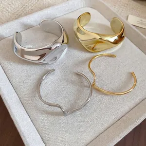 Minimalist irregular wrinkled open cuff bracelets in polished gold and silver finishes